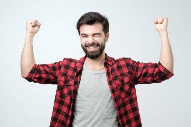 Happy successful young man screaming Yes and raising clenched fists