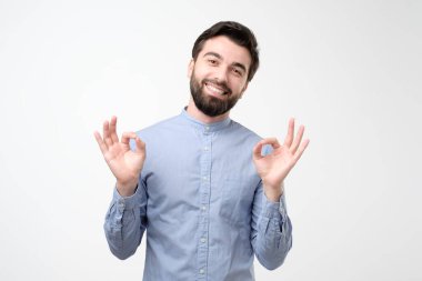 Latin kökenli genç adam, tamam işareti hafif arka plandaki duygularla tatmin oluyor.