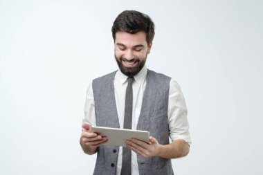 Tuş takımlı çekici İspanyol adam tabletten haber okurken gülümsüyor. Stüdyo çekimi