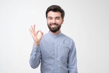 Latin kökenli genç adam, tamam işareti hafif arka plandaki duygularla tatmin oluyor.