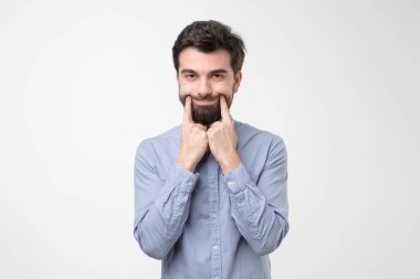 Hiçbir şey onu neşelendiremez. Üzgün genç adam gülümsemesini parmaklarıyla kaldırmaya çalışıyor. Negatif yüz insani duygu.