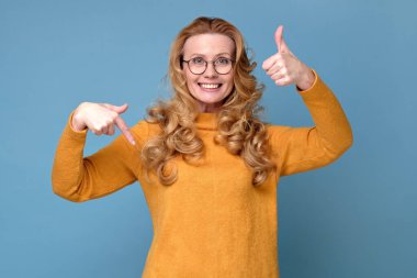 Kendinden emin bir kadın yaptıklarıyla gurur duyar, kendini gösterir, gururunu okşar, başını kaldırır, başparmağını kaldırır. Olumlu yüz insani duygu. Stüdyo çekimi