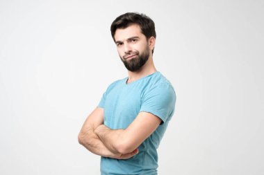 Hoşnutsuzluk içinde kaşlarını çatan genç İspanyol adam, kollarını kavuşturuyor. Stüdyo çekimi