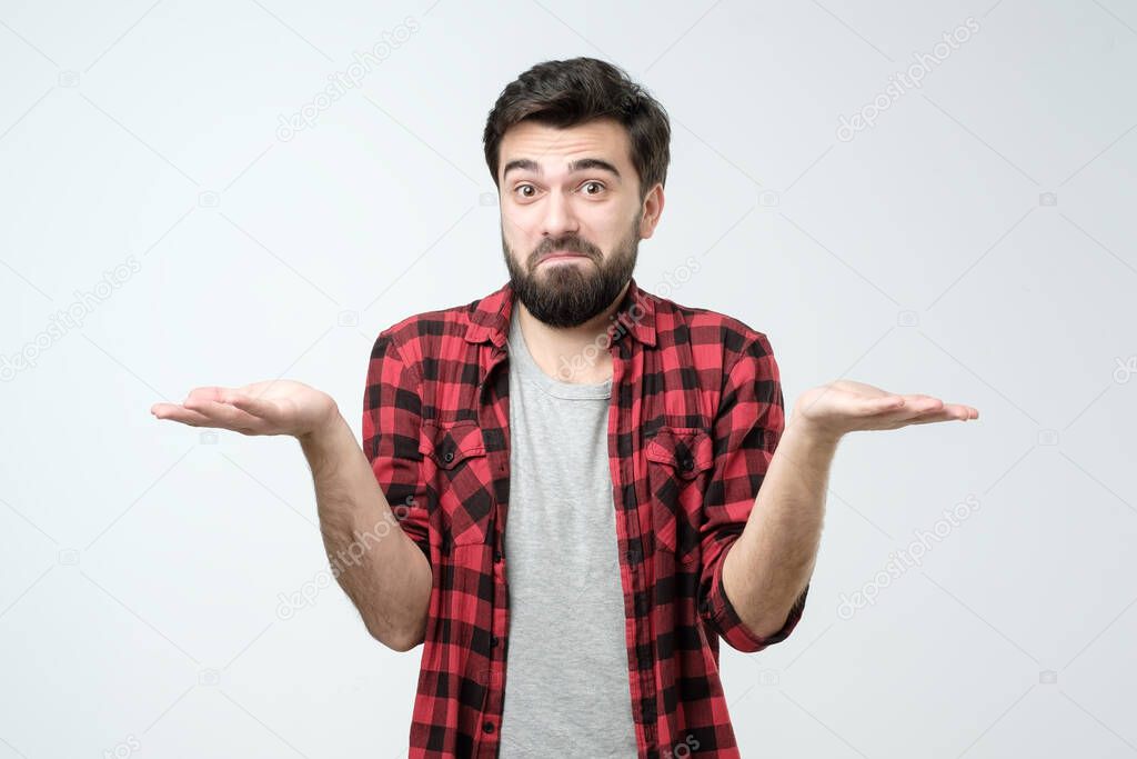 Confused hispanic man giving I dont know gesture on white background. Guy does not know what to choose.