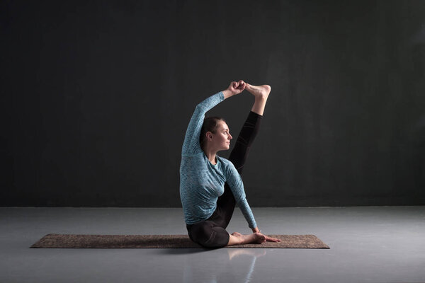 Sporty girl yoga workout, sitting in Heron pose, Krounchasana. Increase strength and flexibility in the joints and muscles of the legs. Studio shot