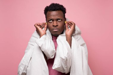 african american youngman inserting ear plugs happy with solution of neighbours