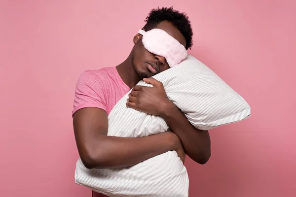 Африканский черный мужчина спит, обнимая подушку в маске для сна. . — стоковое фото