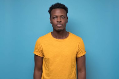 Portrait of African American man in yellow shirt against blue background.