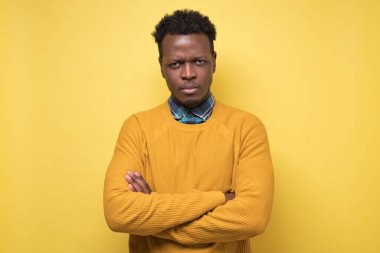 Sarı kazaklı genç Afro-Amerikan adam kameraya ciddi bakıyor..