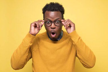 Sarı kazaklı, ağzı açık gezen Afro-Amerikalı genç bir adam.