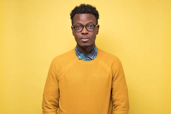 Joven afroamericano hombre en suéter amarillo mirando en serio a la cámara . — Foto de Stock