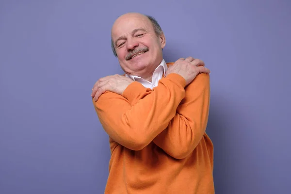 Zadowolony Starszy Mężczyzna Pomarańczowym Swetrze Przytula Się Wysokie Poczucie Własnej — Zdjęcie stockowe