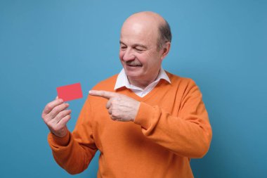 Mutlu İspanyol asıllı kel adam, reklam kartı reklamında parmağıyla kameraya gülümsüyor. Adam kredi kartıyla ödeme yapacak, alışveriş yapacak.