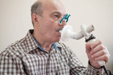 Kıdemli İspanyol adam spirometri ile nefes alma fonksiyonlarını test ediyor. Akciğer hastalığında solunum fonksiyonu teşhisi