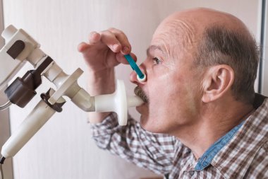Kıdemli İspanyol adam spirometri ile nefes alma fonksiyonlarını test ediyor. Akciğer hastalığında solunum fonksiyonu teşhisi