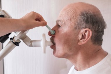 Kıdemli İspanyol adam spirometri ile nefes alma fonksiyonlarını test ediyor. Akciğer hastalığında solunum fonksiyonu teşhisi