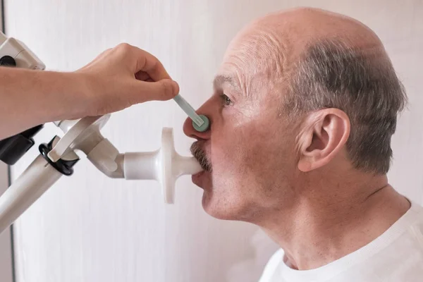 Kıdemli İspanyol adam spirometri ile nefes alma fonksiyonlarını test ediyor. Akciğer hastalığında solunum fonksiyonu teşhisi