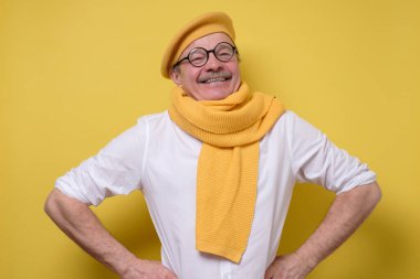 Sarı eşarplı, şapkalı ve bıyıklı yakışıklı adam gururlu, kibirli ve kendinden emin, tatmin olmuş ve başarılı görünüyor..