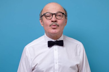 Hoş görünümlü, yuvarlak dudaklı, havada öpüşen, büyük bir sevgi ve şefkatle bakan son sınıf öğrencisi. Stüdyo resmi mavi duvarda