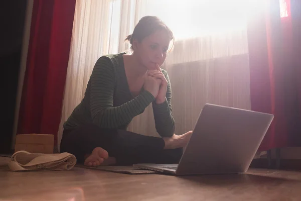年轻漂亮的姑娘坐在客厅的笔记本电脑旁 网上有课 — 图库照片