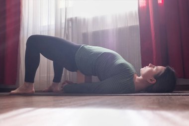 Kafkasyalı genç kadın evdeki oturma odasında yoga egzersizi yapıyor..