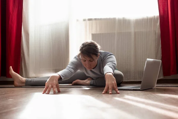 Mulher praticando ioga, fazendo variação Janu Sirsasana na sala de estar em casa — Fotografia de Stock