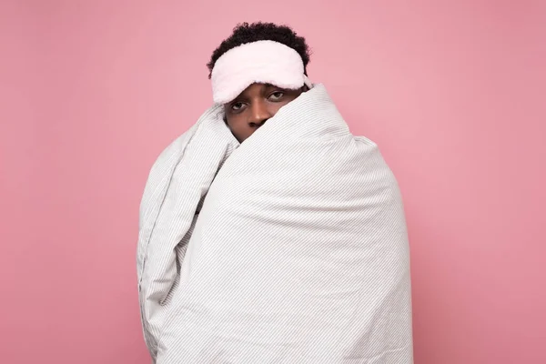 Homem de cabelos escuros sonolento em máscara médica segurando cobertor branco — Fotografia de Stock