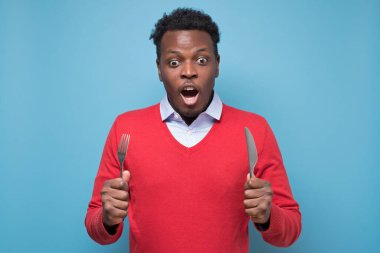 Bıçaklı ve çatallı genç Afro-Amerikalı adam lezzetli yemeklerle şoke oldu..