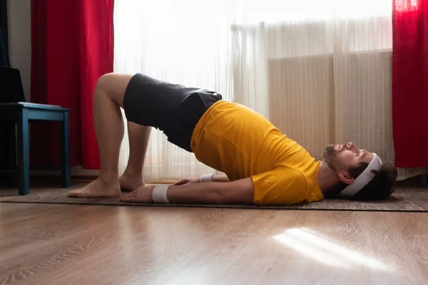 Genç adam oturma odasında yoga yaparken poz veriyor. — Stok fotoğraf