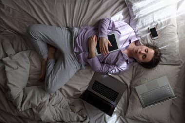 Kafkasyalı genç bir kadın evde dizüstü bilgisayar ve telefonla çalışmaktan yorulmuş. Üst görünüm