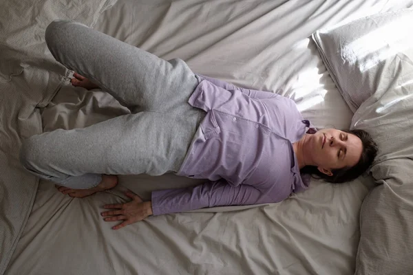 Young woman in ardha chakrasana yoga pose on bed in the morning. Top view