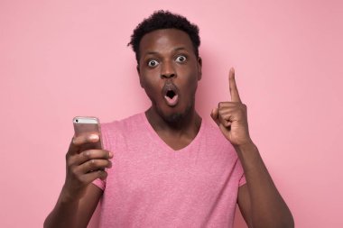 Afrikalı Amerikalı bir adam şok olmuş bir suratla bankasından mesaj aldı. Stüdyo resmi pembe duvarda..