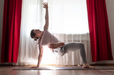 Beyaz kadın evde Vasisthasana varyasyonu ya da Yan Plank yoga pozu yapıyor..
