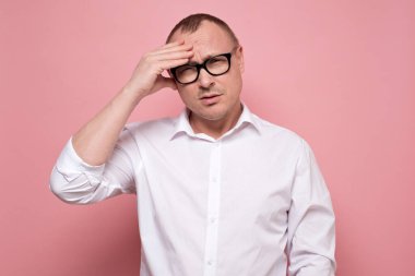Gözlüklü stresli genç adam bir şeyden pişmanlık duyuyor, kameraya bakıyor. Çok çalışan, memnun olmayan, bitkin ve bunalmış bir adam. Stüdyo resmi pembe duvarda..
