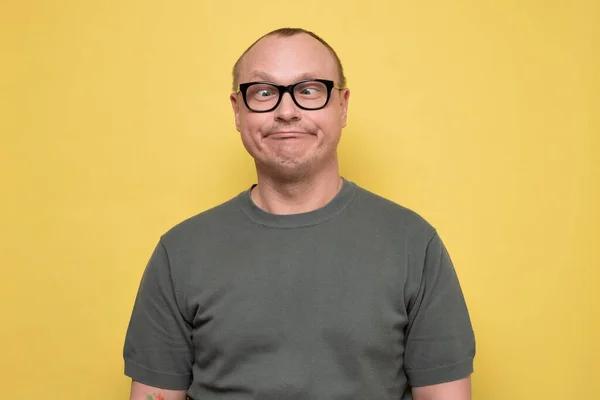 Loco buscando hombre en gafas haciendo caras graciosas entrecerrando los ojos — Foto de Stock