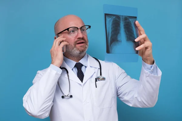 Лікар тримає рентген грудей, що розмовляють по телефону з пацієнтом — стокове фото