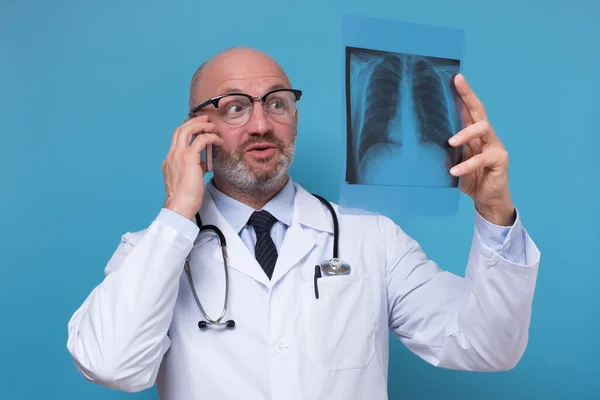Лікар тримає рентген грудей, що розмовляють по телефону з пацієнтом — стокове фото