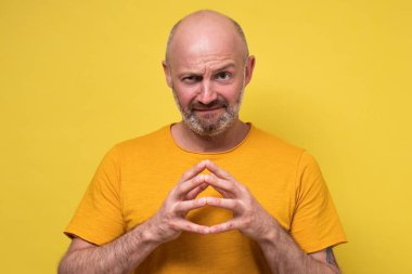 Kurnaz, olgun, beyaz bir adam, kameraya sinsice bakıyor ve bir plan yapıyor.