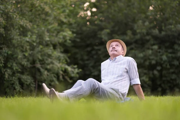 Oudere Spaanse man rustend, op frisse lucht liggend op de grond omhoog kijkend. — Stockfoto