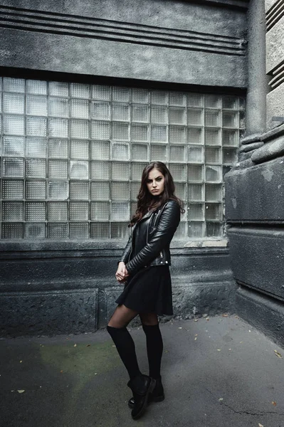 Mujer hermosa oriental con chaqueta de ciclista posa en el patio trasero de la casa de apartamento vintage — Foto de Stock