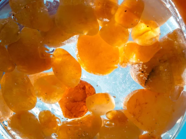 Small amber stone in a glass jar with water. Natural mineral. Alternative medicine.