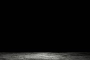 Light shining down on dirt gray cement floor in dark room with copy space, abstract background