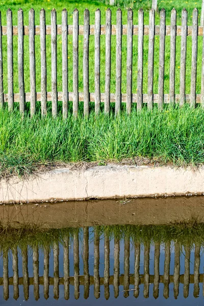 Wood fence is reflected in the water — Stock Photo, Image