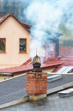 Beyaz duman bacasından yükselir ve çatılarda çizer