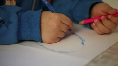 Beyaz kağıda renkli kalemle resim çizen çocuk