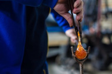 Cam üfleyici güzel bir cam parçası oluşturuyor. Bir cam ustası yanıyor ve bir sanat eserini üflüyor.. 