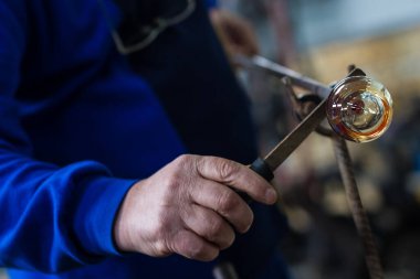 Cam üfleyici güzel bir cam parçası oluşturuyor. Bir cam ustası yanıyor ve bir sanat eserini üflüyor.. 