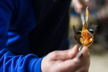 Beloslav / Bulgaristan - 5 Mayıs 2019: Cam üfleyici güzel bir cam parçası oluşturuyor. Bir cam ustası yanıyor ve bir sanat eserini üflüyor.. 