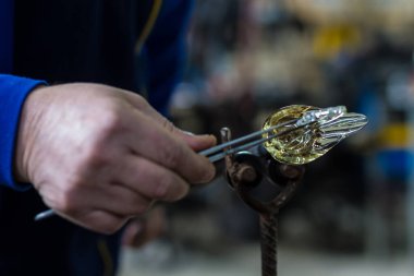 Beloslav / Bulgaristan - 5 Mayıs 2019: Cam üfleyici güzel bir cam parçası oluşturuyor. Bir cam ustası yanıyor ve bir sanat eserini üflüyor.. 