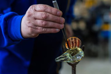 Beloslav / Bulgaristan - 5 Mayıs 2019: Cam üfleyici güzel bir cam parçası oluşturuyor. Bir cam ustası yanıyor ve bir sanat eserini üflüyor.. 